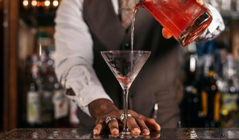 Bartender pouring a red cocktail into a martini glass, representing how to get a liquor license for serving mixed drinks in New York.